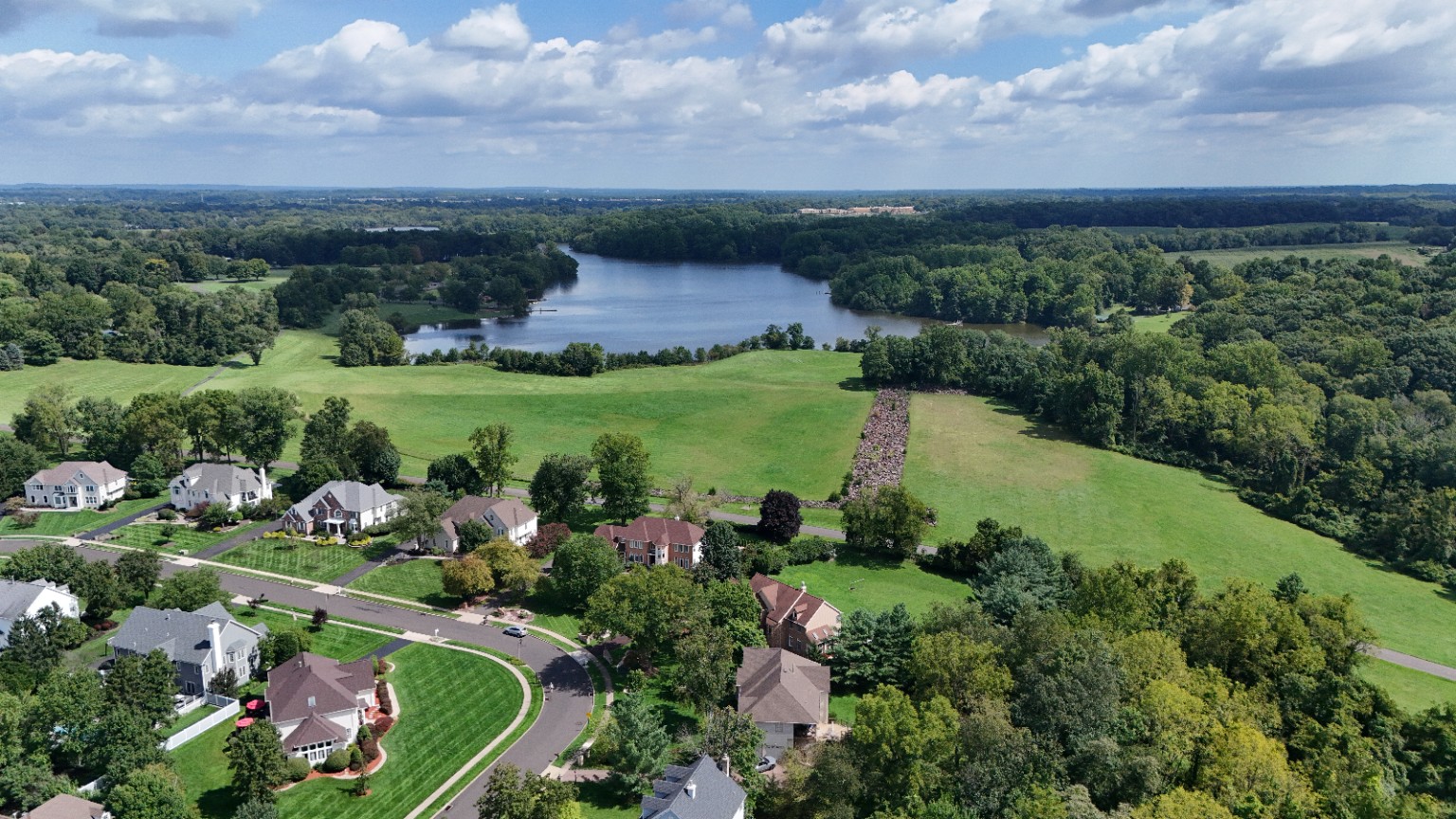 Aerial view of a residential neighborhood beside open fields and a lake