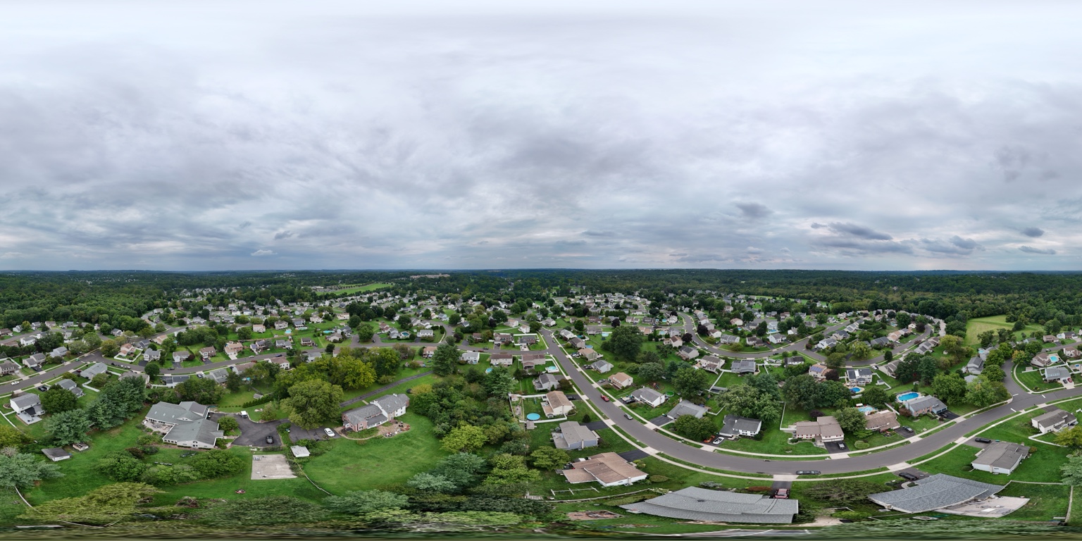 Wide aerial panorama of a neighborhood beneath a cloudy sky